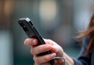 Person holding a smartphone with a microphone attachment